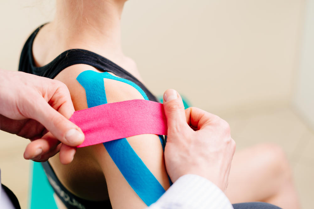 Physiotherapeut behandelt Schulter mit Kinesiotaping in der Physiotherapie in Dresden